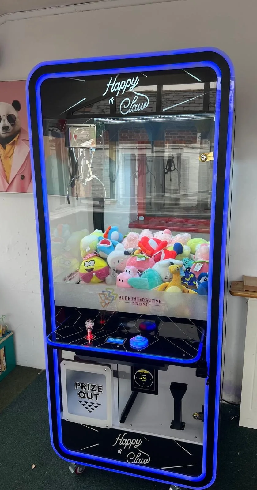 Happy Claw blue-lit claw machine full of plush prizes with a prize-out door