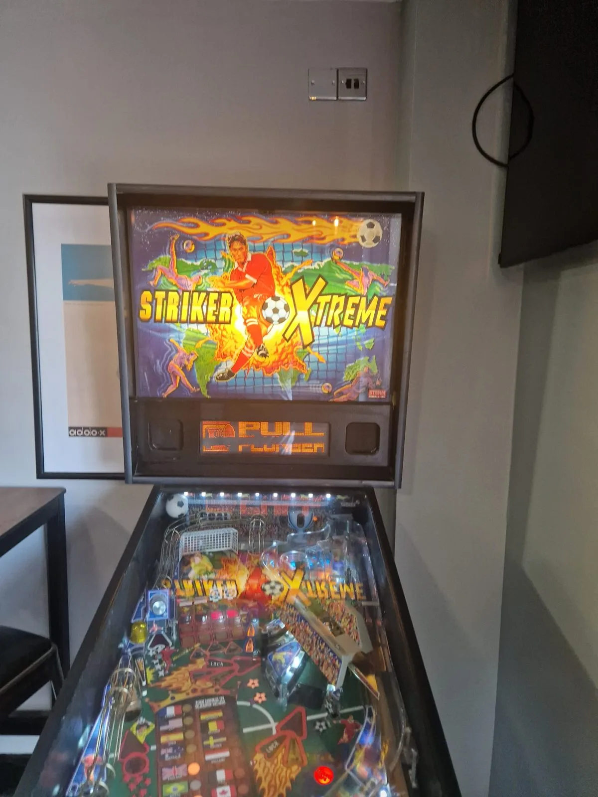 Stern Striker Xtreme pinball, full machine front view with backglass lit
